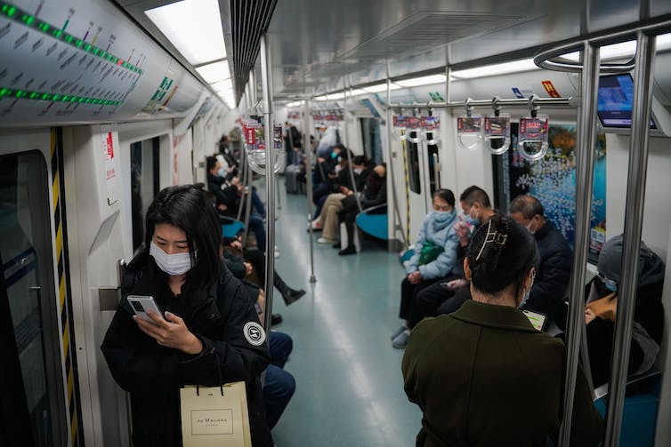 Voyageurs dans une gare à Beijing portant le masque