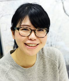 Une jeune femme japonaise avec des lunettes en écaille de tortue souriant à la caméra
