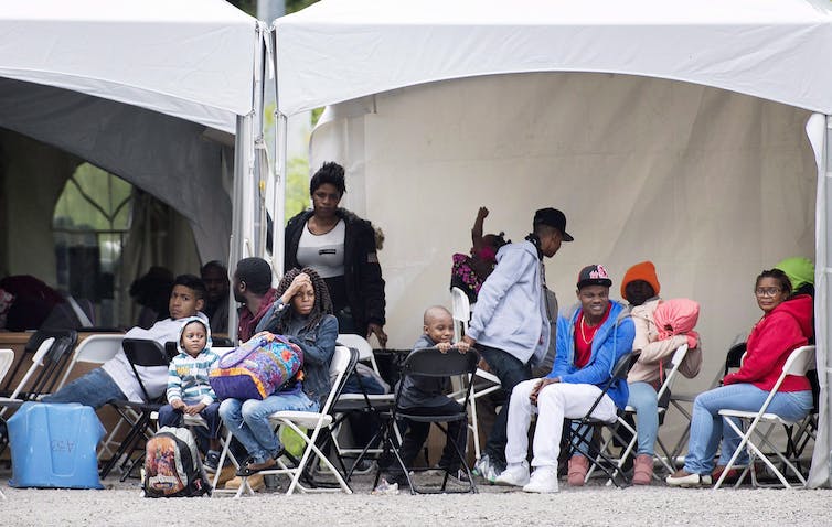 Des hommes, des femmes et des enfants sont assis sous une tente