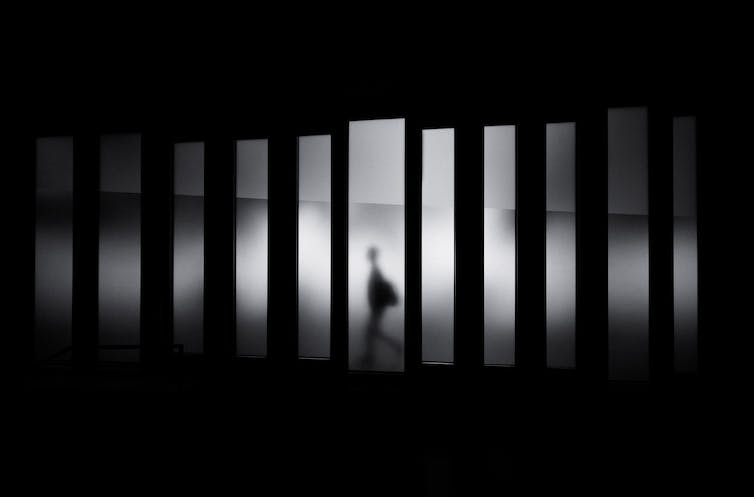 Une silhouette floue se déplace dans une image fragmentée, en noir et blanc