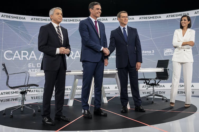 Trois hommes en complet cravates posent debout, au côté d’une femme vêtue de blanc
