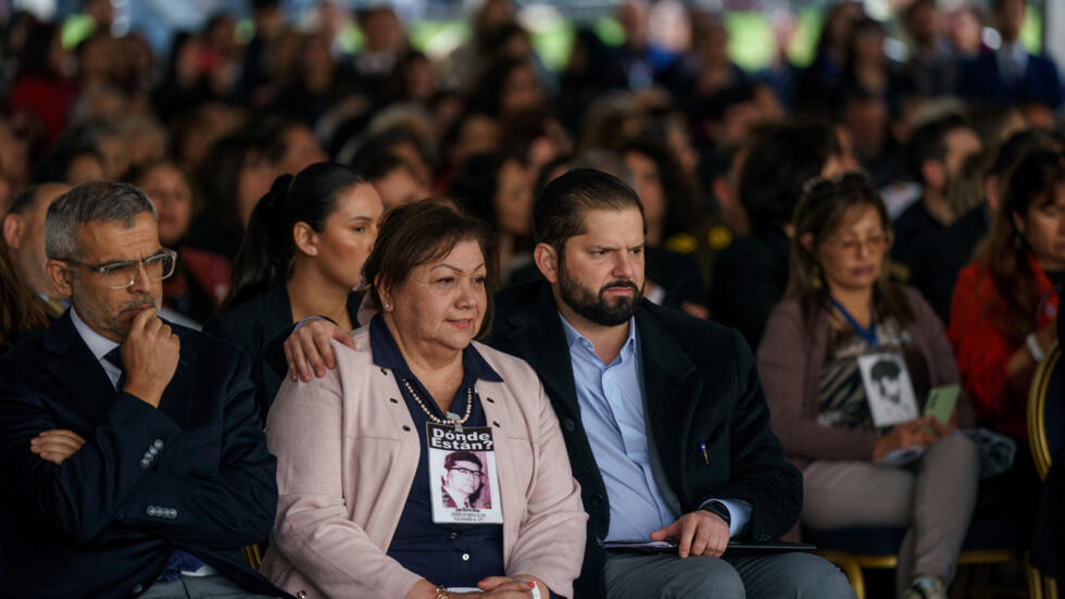 Le président chilien Gabriel Boric se tient près d'une proche d'un disparu pendant que le gouvernement annonce un plan national de recherche des disparus de la dictature, le 30 août 2023 à Santiago.