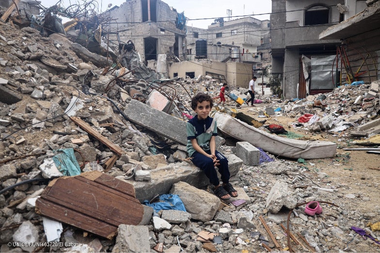 enfant assis sur les ruines de bâtiments bombardés à Gaza
