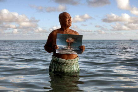 Angelo Tehuira-Hioe, 64 ans, tient une photo d’une explosion nucléaire © Adam Ferguson / The New York Times-Redux / RÉA