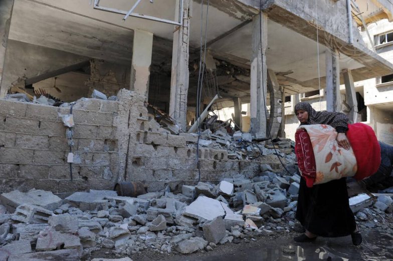 Une résidente palestinienne marche derrière un bâtiment détruit par les frappes aériennes israéliennes à Gaza. Les violences basées sur le genre touchent les femmes et les filles de manière disproportionnée.