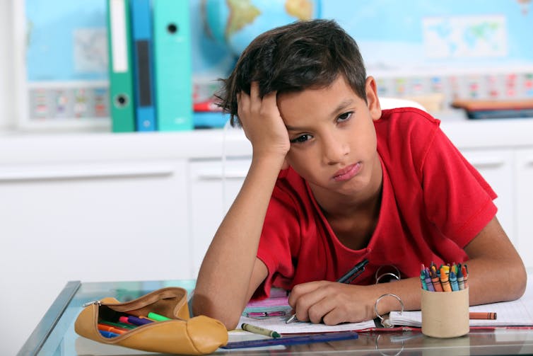 Un enfant a l’air de s’ennuyer à son bureau