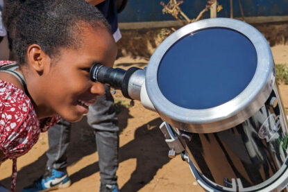 Une petite fille malgache regarde dans un télescope l’image du Soleil