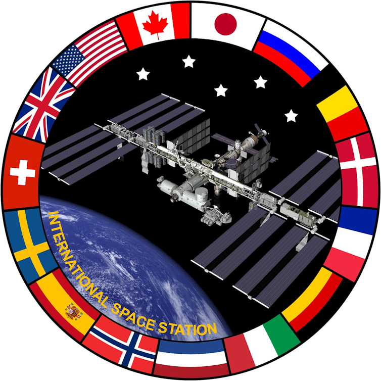 Un emblème représentant une photo de la Station spatiale internationale, entourée d’un anneau où figurent les drapeaux des pays partenaires