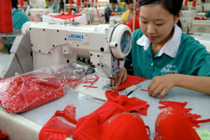 Une femme coud un soutien-gorge rouge dans usine textile en Chine.